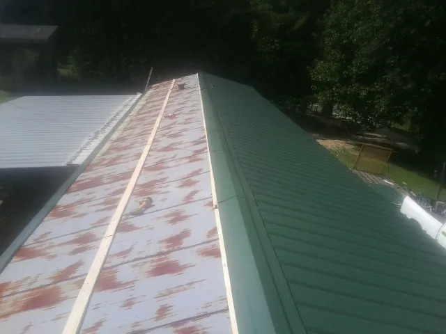 Old rusted panels beside newly installed green metal roofing — Wind Damage Roof Repair by Roofing Brothers in Melbourne Beach