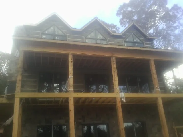Dormers and porch framing on a large log home under construction — Roof Coating work by our crew in Melbourne Beach