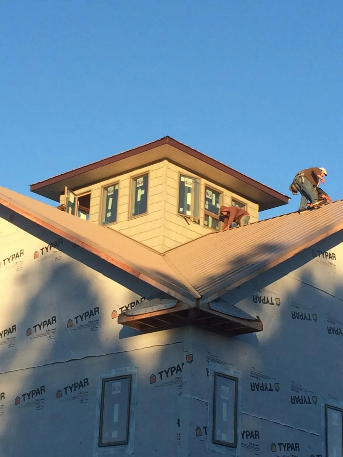 Roofers working around a rooftop cupola on a new metal roof at sunset — Roof Waterproofing in Melbourne Beach by Roofing Brothers